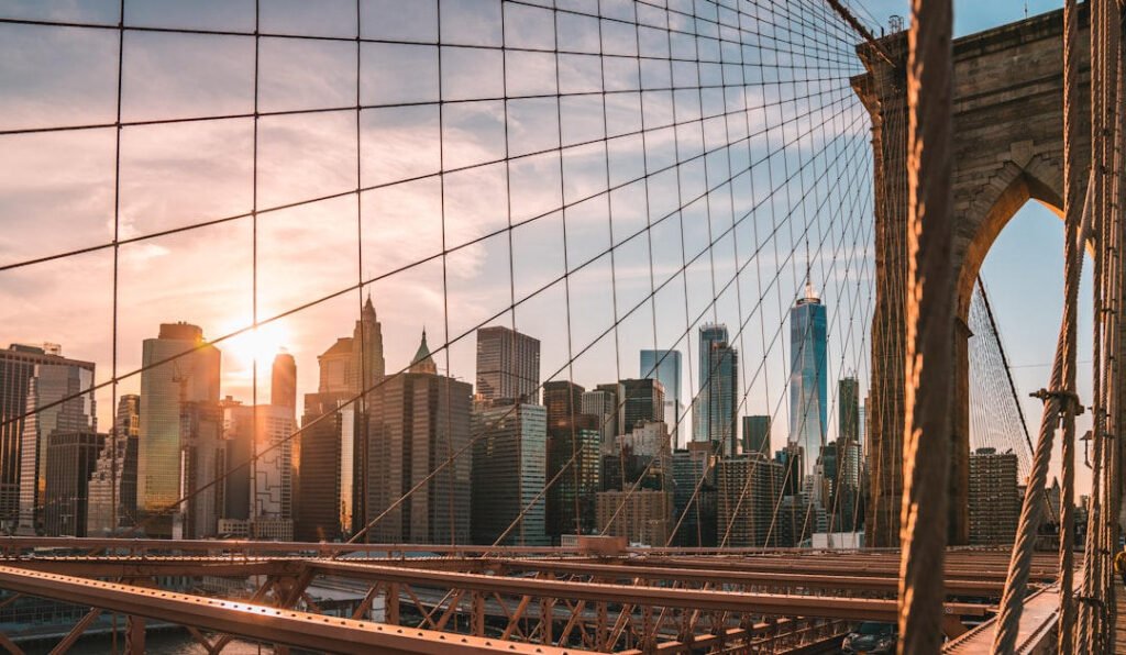 Pedestrians walking across the Brooklyn Bridge with the Manhattan skyline at sunset