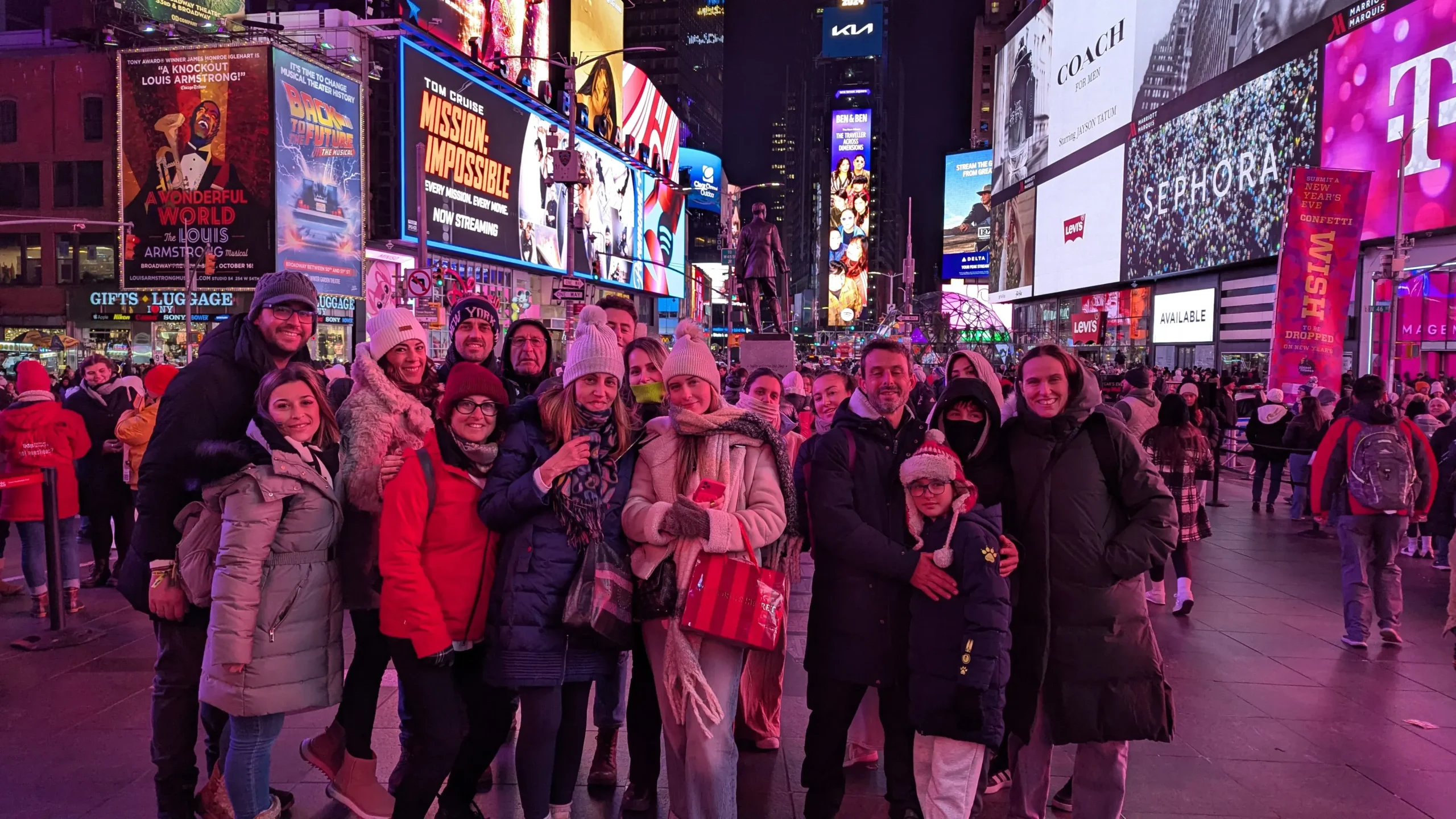 Group of people posing together in Times Square, surrounded by bright advertisements.
