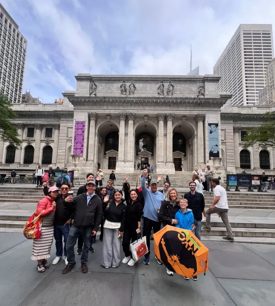 Group of people posing in front of a historic library building.