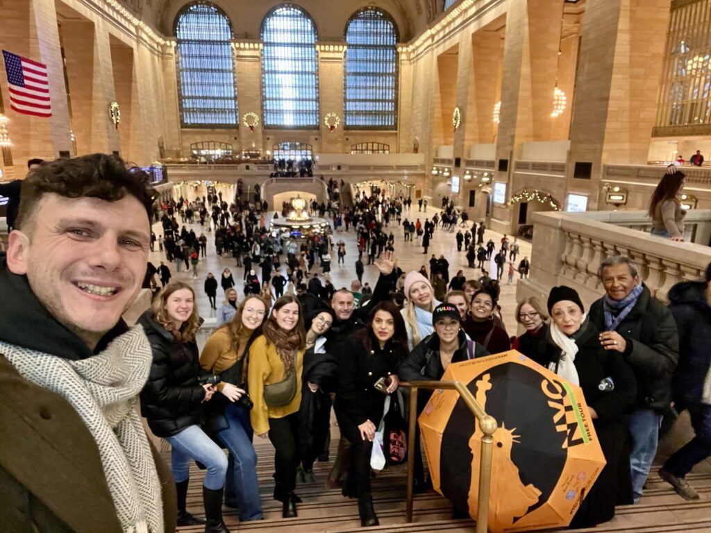 Our guide with the orange-and-black Statue of Liberty umbrella leading a group at Grand Central Terminal
